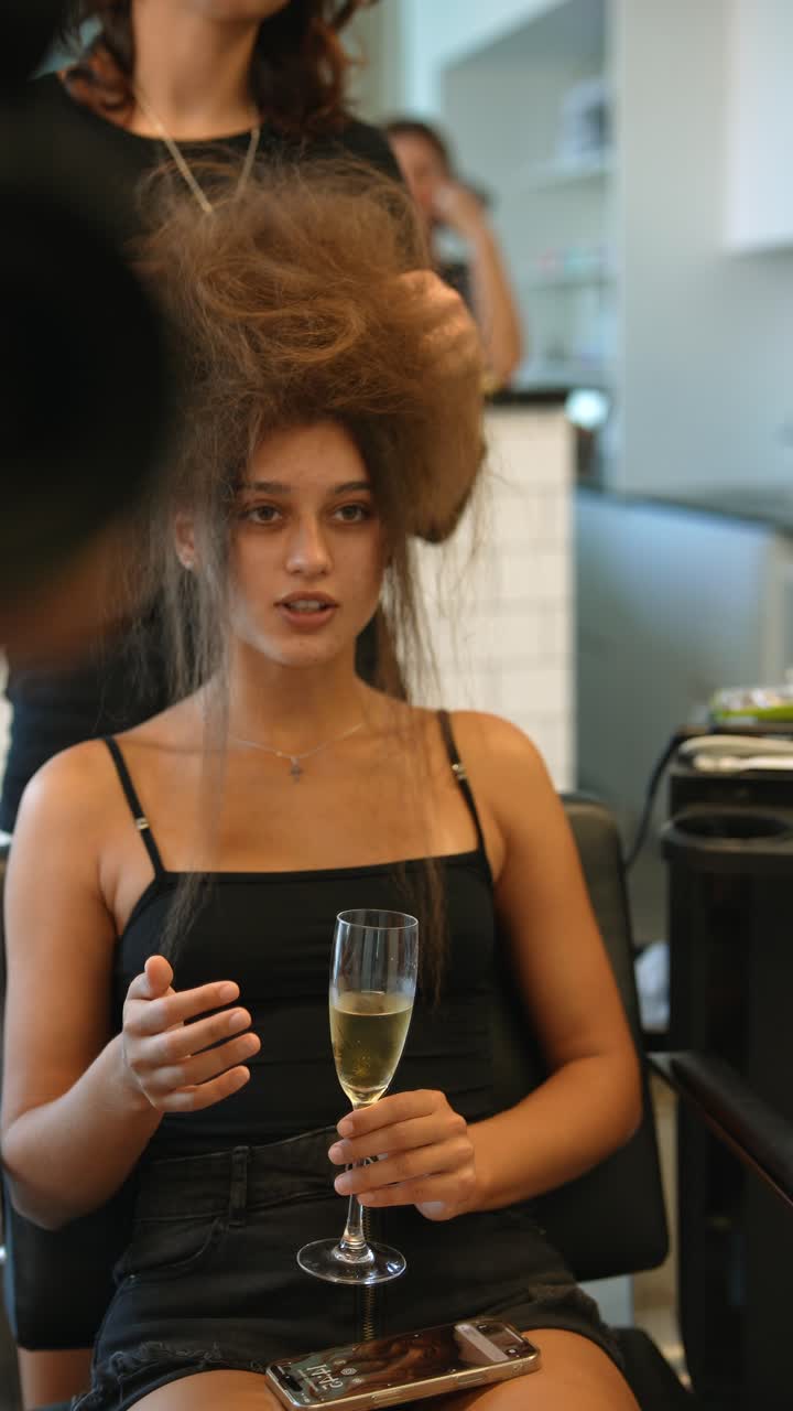 Junge Frau beim Haarstyling mit Champagnerglas