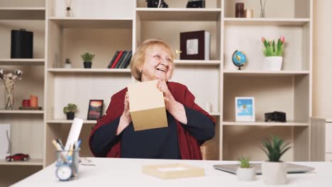 elderly-woman-happily-opens-a-package-in-a-cardboard-box