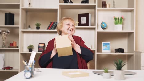 elderly woman happily opens a package in a cardboard box