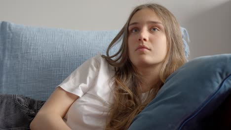 Close-up-of-woman-using-tv-remote-and-resting-head-on-the-pillow,-in-Slow-Motion