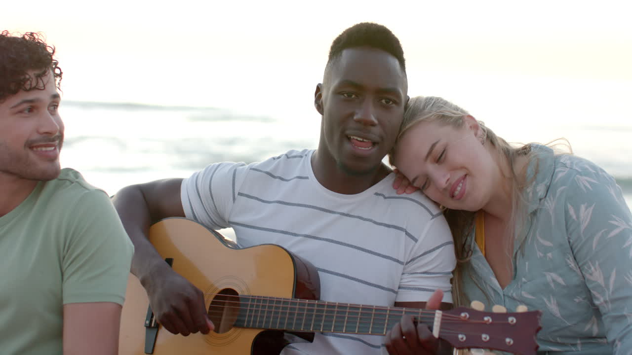 Giovane uomo afroamericano suona la chitarra all'aperto a una festa in spiaggia