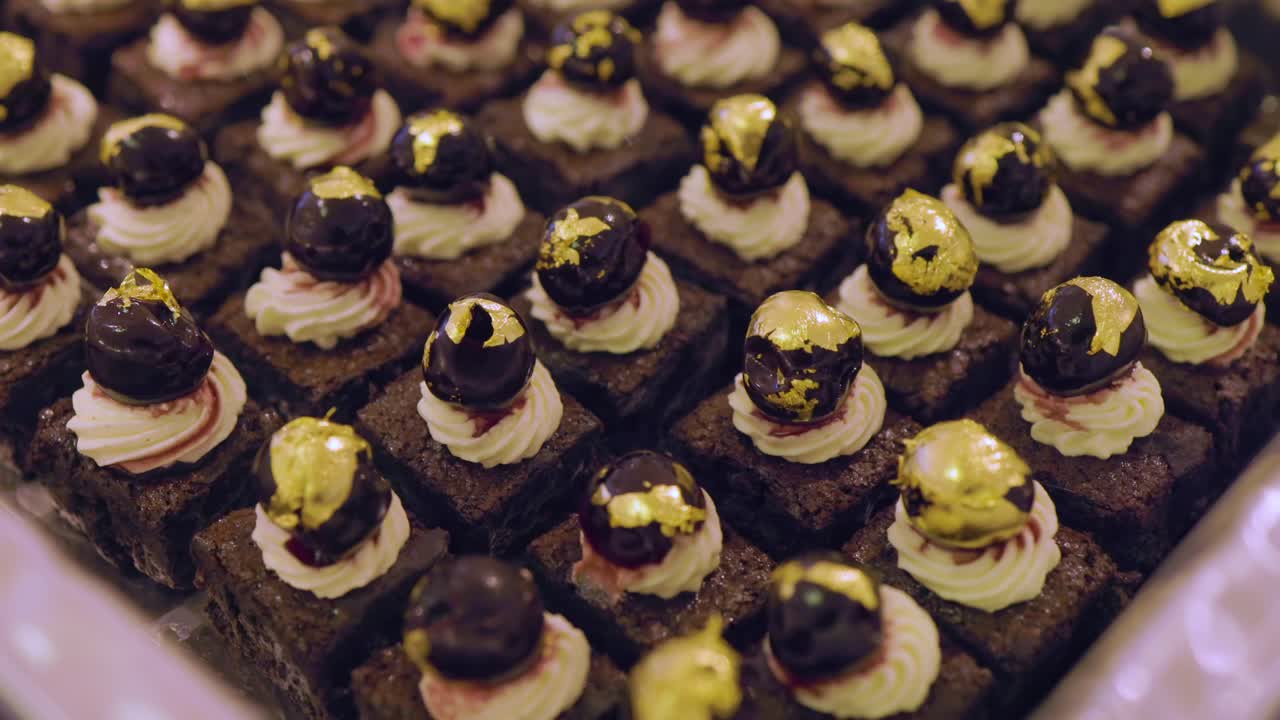 Exquisite desserts with dark chocolate bases, pristine white cream swirls, and polished spheres. Topped with gold leaf, they promise a luxurious blend of texture and flavor. True culinary art!