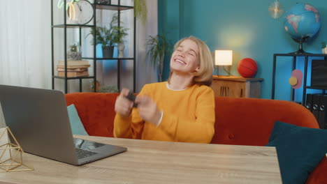 teenager boy playing sports simulator game on laptop with joystick celebrating goal victory at home