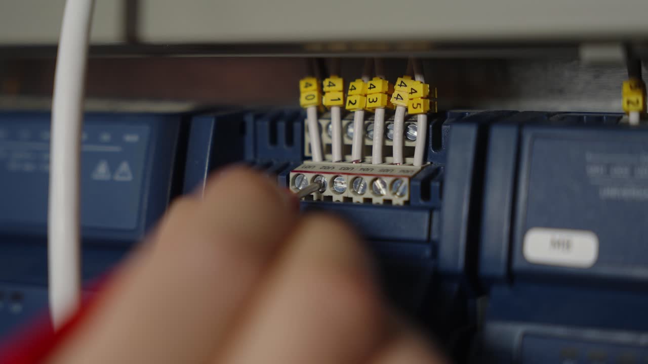 estrecho de la mano de un electricista con una herramienta de medición e inspección de la salida eléctrica de los fusibles en una caja de fusibles