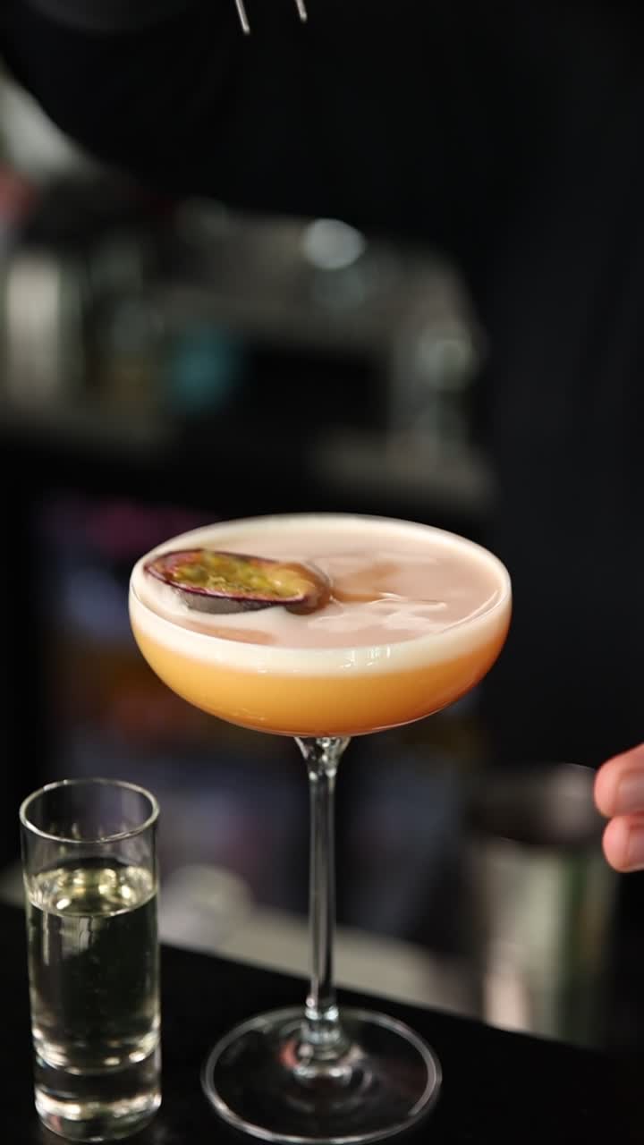 Barman che guarnisce un cocktail al frutto della passione con le pinze