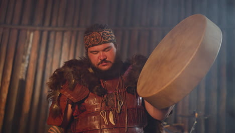 man in spiritual ecstasy taps shamanic drum at ritual