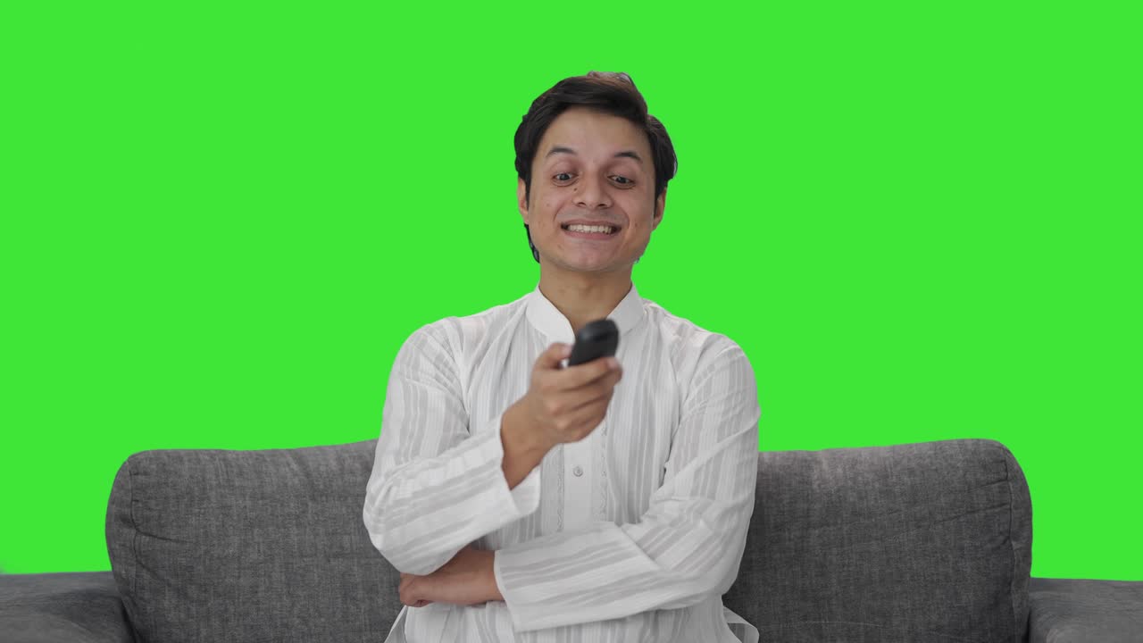 Indisk mand griner, mens han ser tv Green screen