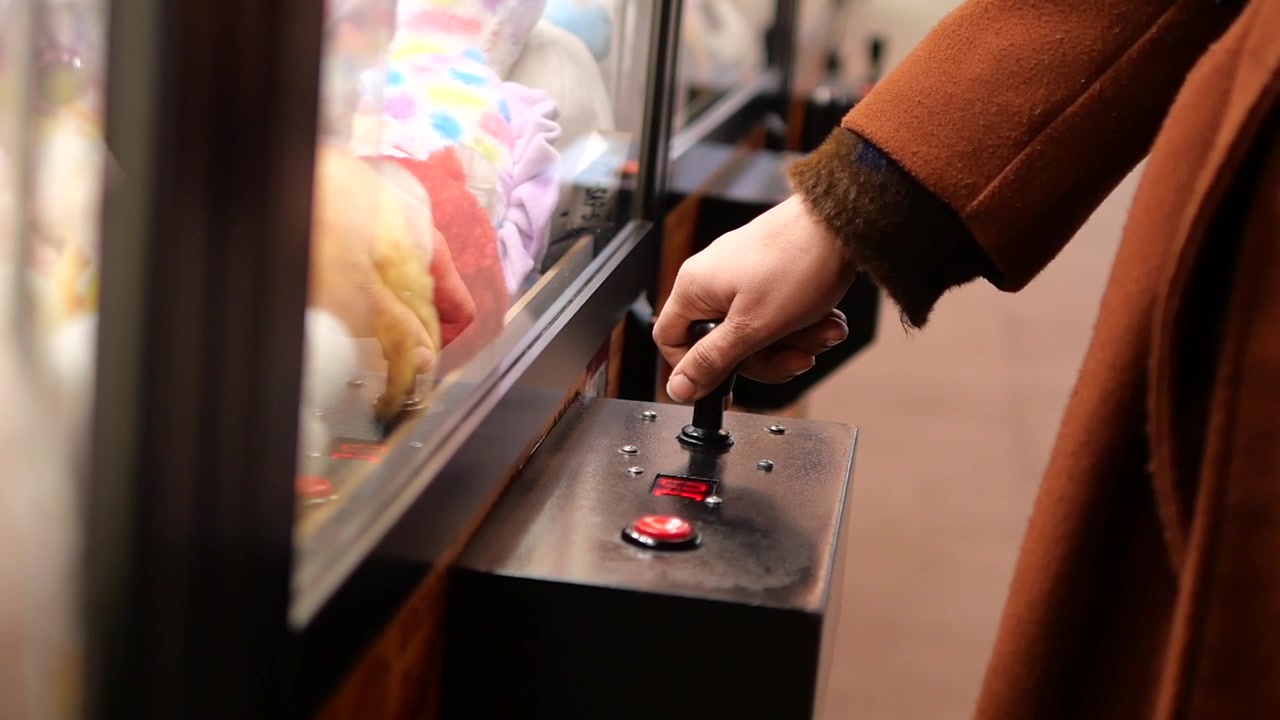 Persona che gioca al gioco della gru in sala giochi