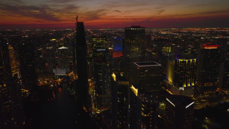 Aerial-descending-footage-of-group-of-modern-high-rise-apartment-buildings-and-residential-boroughs-under-red-twilight-sky-in-background.-Miami,-USA