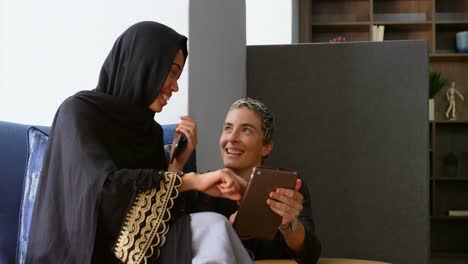 mujeres ejecutivas discutiendo en una tableta digital en la oficina 4k