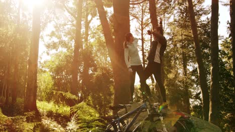 excited mountain biking couple standing on a rock