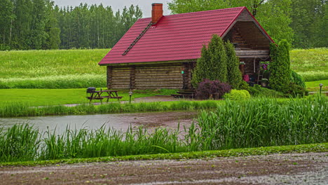 Un-Exuberante-Campo-Verde-Con-Una-Hermosa-Casita-De-Madera-Con-Techo-Rojo-Y-Chimenea