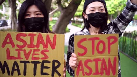 asian women with posters during protest in city