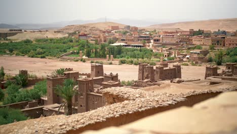 moroccan village in a desert oasis with green palm trees on a hot sunny day, rising handheld shot