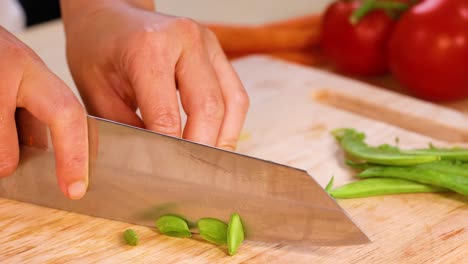 cortar guisantes verdes en una tabla de cortar de madera