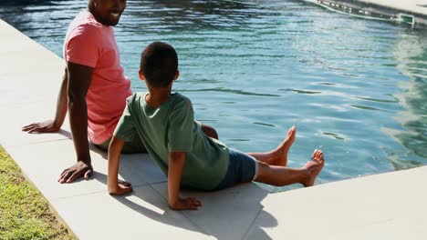 Padre-E-Hijo-Sentados-Al-Borde-De-La-Piscina