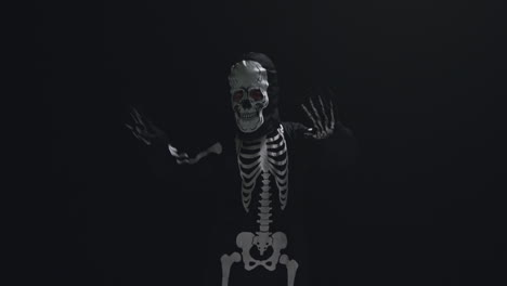 fotografía de estudio de un niño vestido con un disfraz de esqueleto haciendo un truco o un regalo en halloween bailando contra un fondo negro 7