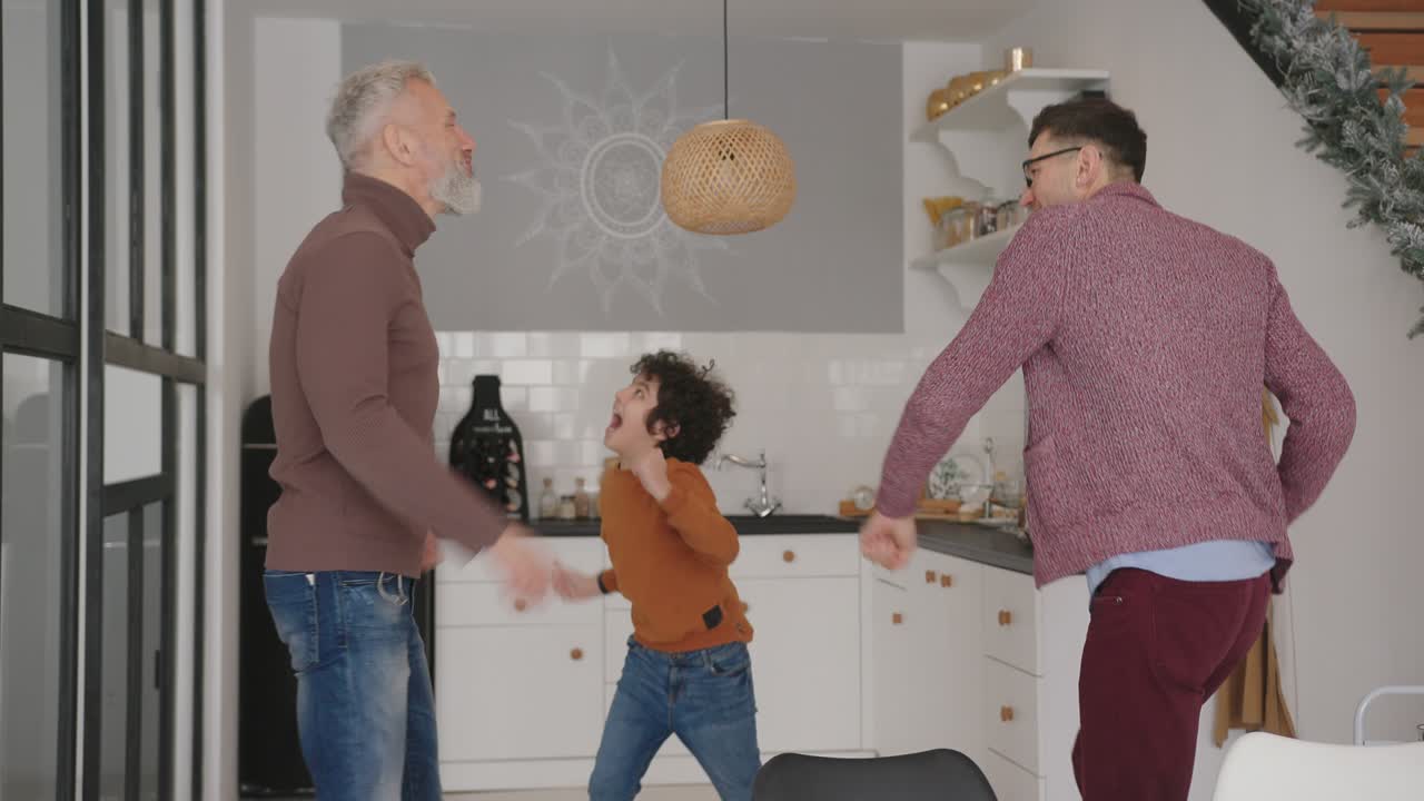 una alegre familia gay disfruta bailando en la cocina de su casa