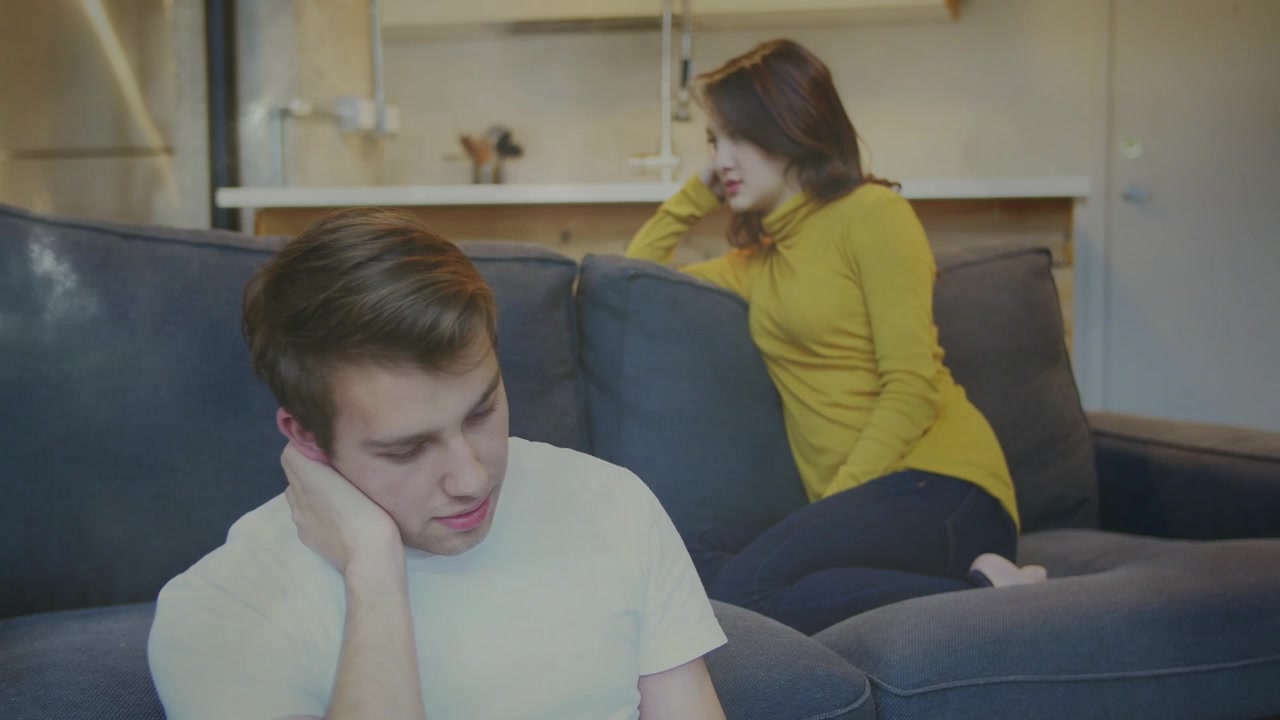 Woman speaking with pensive man on sofa, initiating health talk while light bloom showing tension