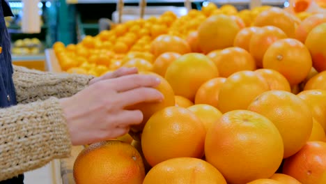 Woman buying fresh grapefruits at grocery store