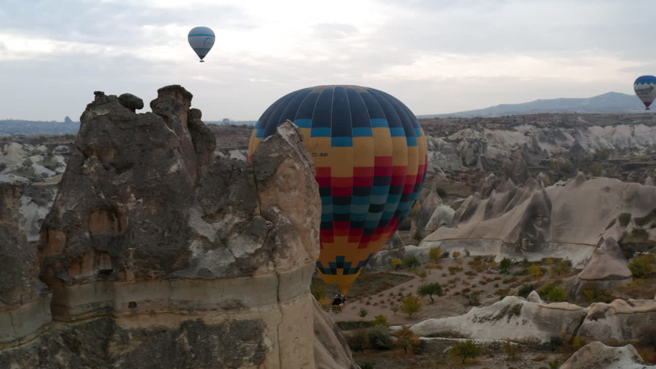 globos aerostáticos volando sobre el paisaje montañoso de capadocia en turquía al amanecer - toma aérea de drones