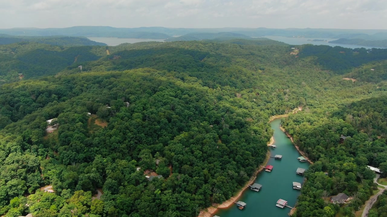 Una ripresa aerea che mostra un'insenatura blu tortuosa del lago Beaver in Arkansas, circondata da fitte foreste verdi e moli privati per barche, perfetta per contenuti di viaggio e immobiliari