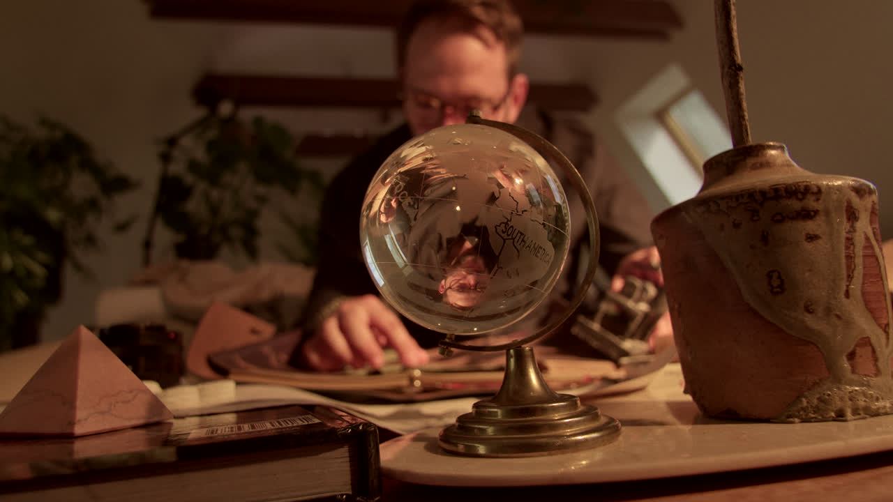 Man Looking at a Globe on His Desk