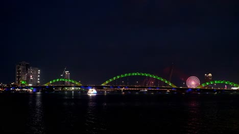 a colorfully lighted tourist boat approaches the dragon bridge in da nang, vietnam, to give tourists a closer look at the spectacular engineering icon.