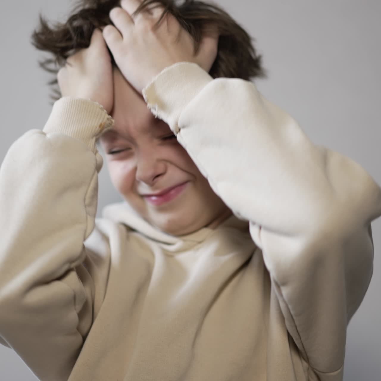 Sleepy teenager rubbing his eyes and face lazily and stretching his arms up. Nice handsome kid with messy hair close up