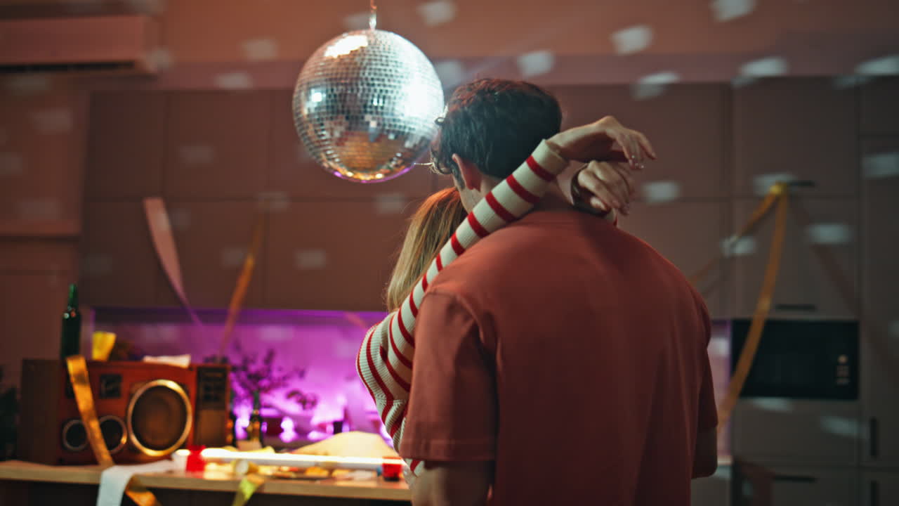 Dancing couple expressing tenderness under disco ball after night party close up