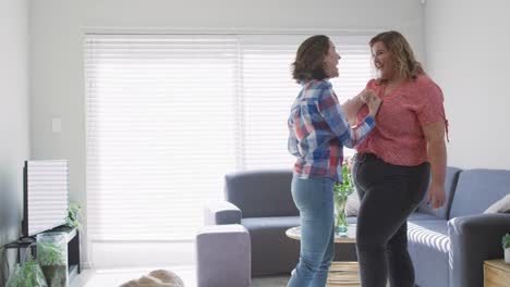 Caucasian-lesbian-couple-dancing-and-smiling-with-dog