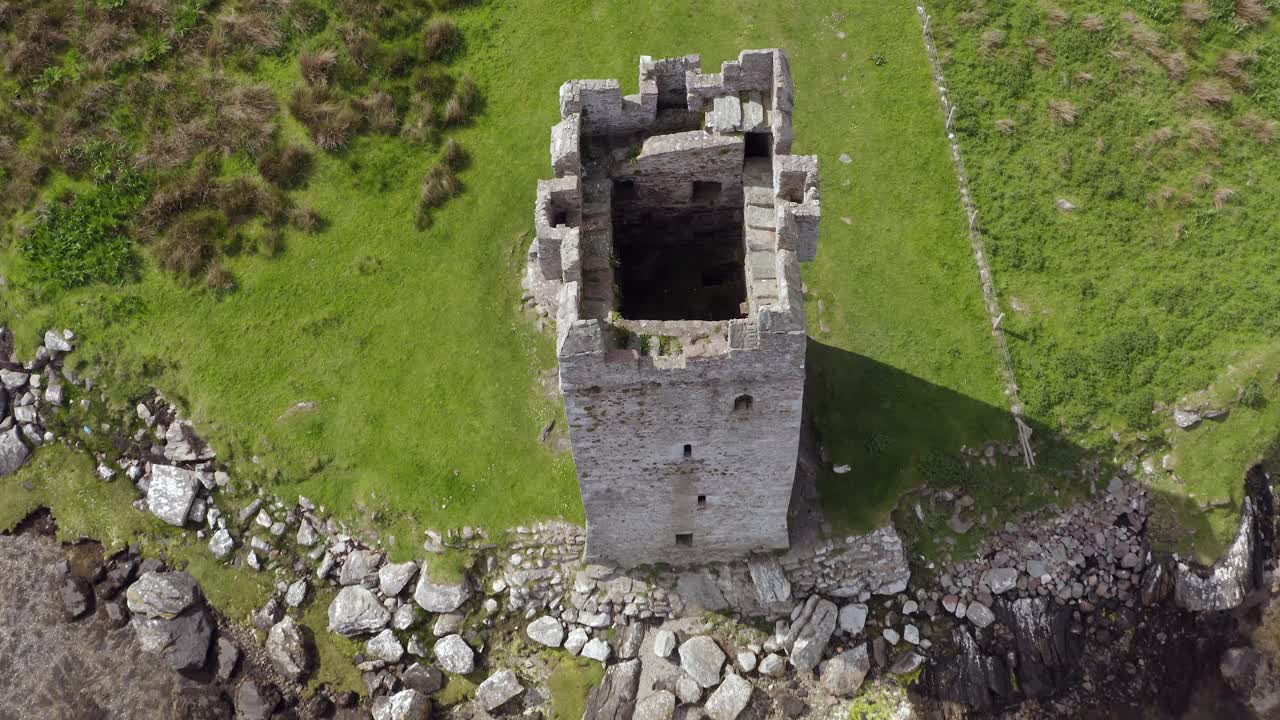 Rising aerial tilt down along irish towerhouse on achill island on sunny day