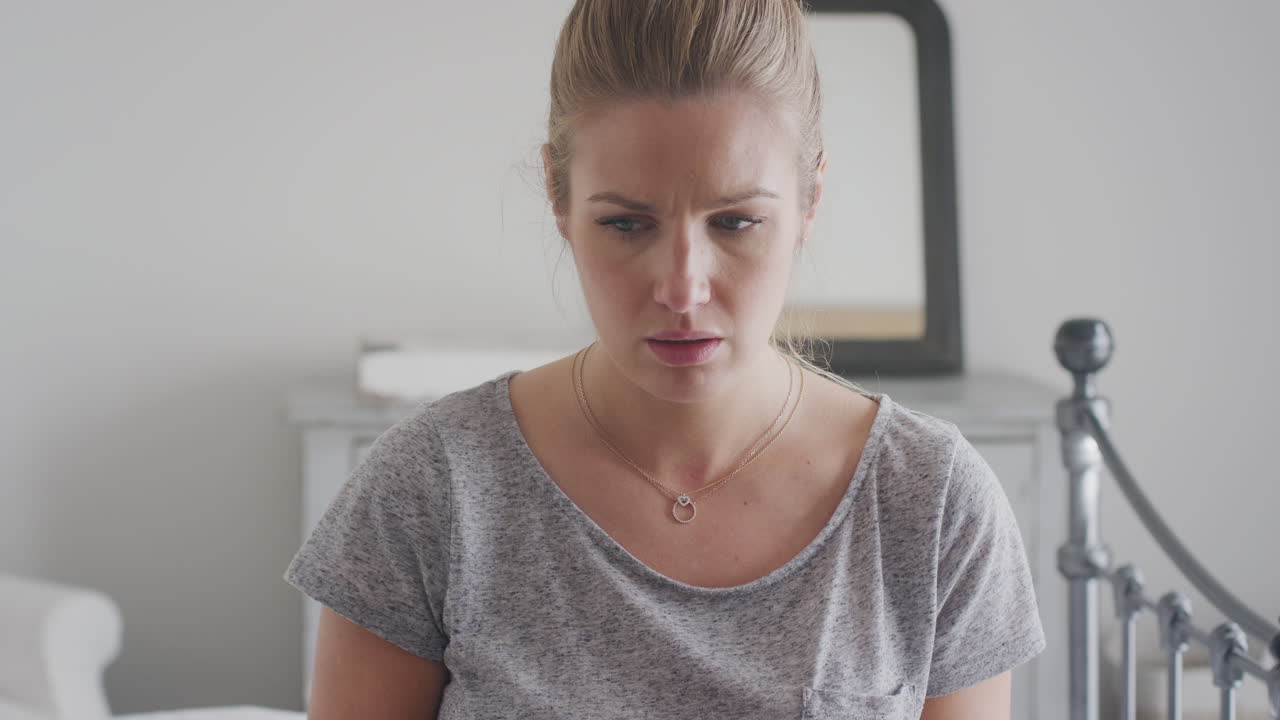 피자마를 입고 침대에 앉아 휴대전화를 들고 있는 불행한 여성이 소셜 미디어를 통해 온라인에서 괴롭힘을 당하고 있습니다.