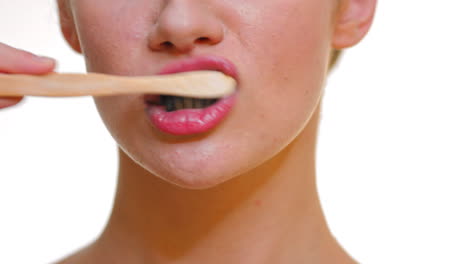 woman cleaning her teeth with a bamboo toothbrush and black carbon toothpaste