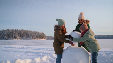 family building a snowman in a beautiful winter landscape