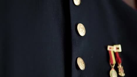 slow tilting shot of a military outfit with golden pins hanging for a wedding