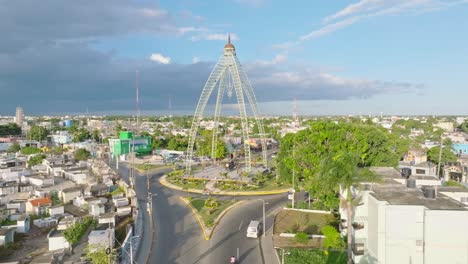 Aerial-approaching-shot-of-monument-at-roundabout-with-traffic-in-SAN-PEDRO-DE-MACORIS-City-at-sunset