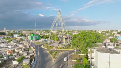 tomada aérea de aproximación del monumento en la rotonda con el tráfico en la ciudad de san pedro de macoris al atardecer