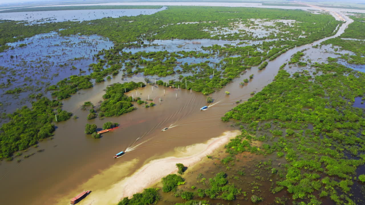 Several colorful boats moving along a waterway near the flooded village of Kampong Phluk, aerial