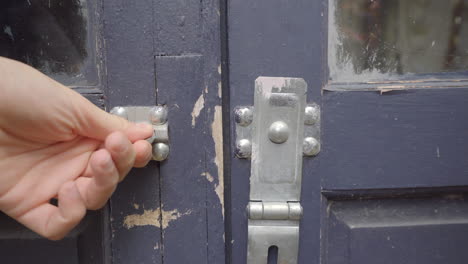 man unlocks padlock of a blue door