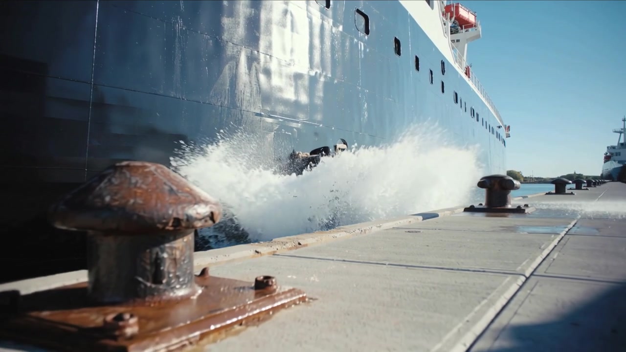 Compressing as vessel settling hull and pneumatic fender pressing on quay forcing spray over cleats