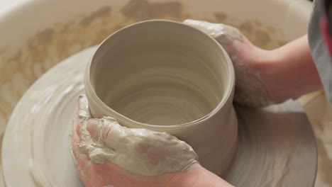 artisan molds delicate vase with practiced hands on throwing wheel in his studio