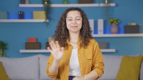 Happy-young-woman-waving-at-camera.