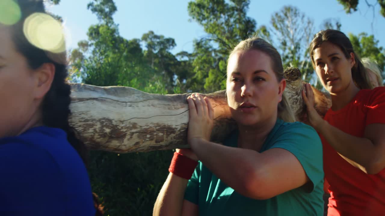 grupo de mujeres en forma que llevan un pesado tronco de madera durante una carrera de obstáculos