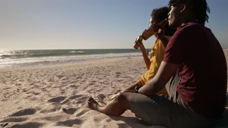 Side-view-of-African-american-couple-drinking-beer-on-beach-in-the-sunshine-4k-