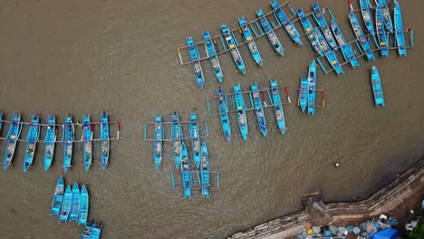 overhead drone shot of rows of fishing boats parked at the fish auction harbor after returning to sea to find fish