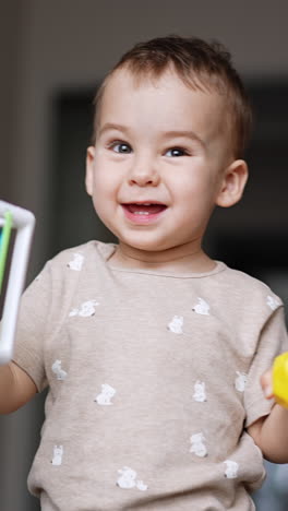 beautiful kid shaking the toy cube walking by the room. baby playing with a toy at home. close up. vertical video