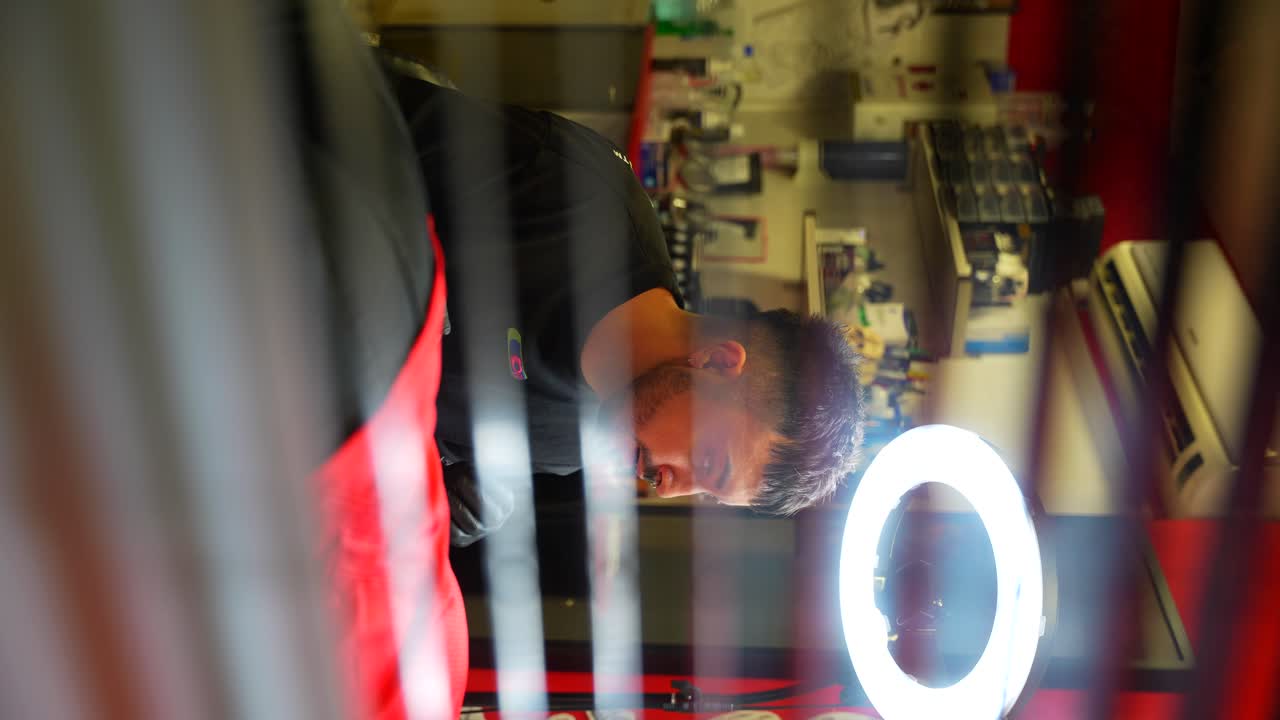 Tattoo artist consulting with a client seen behind a half-open curtain. Vertical