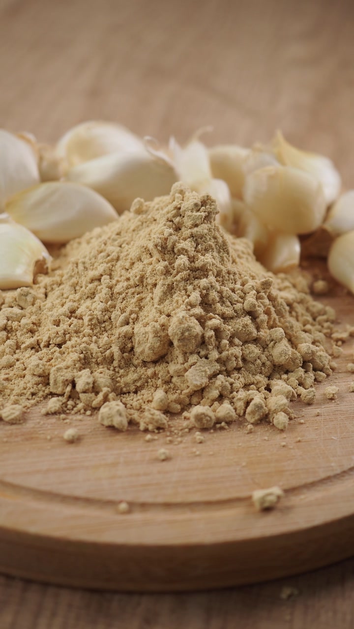 Garlic Powder and Fresh Cloves on a Wooden Cutting Board