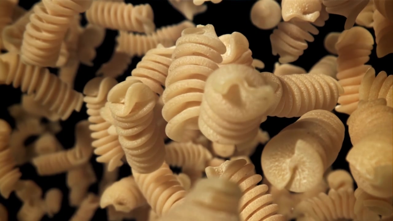 Fusilli secchi che cadono al rallentatore su sfondo nero